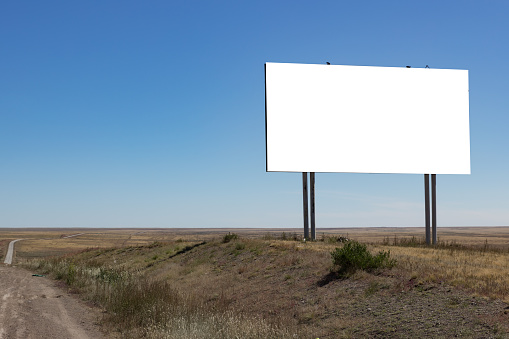 Blank billboard on the road in the steppe with blue sky. Mongolia