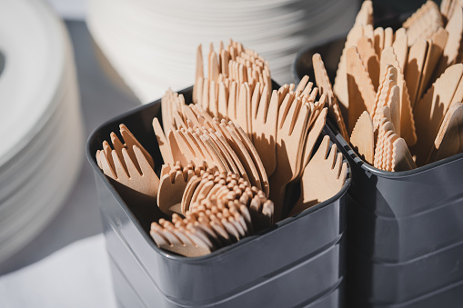 Wooden forks and knives in grey basket. Eco-friendly cutlery. Eco-friendly disposable tableware. Refusal of plastic. The concept of caring for nature
