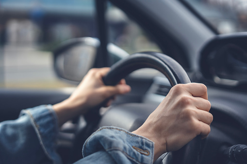 Tense hands of a female driver on the steering wheel in a car. Stress while driving a car concept
