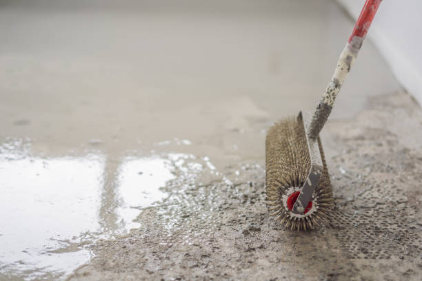 istock plasterer during floor covering works with self-levelling cement mortar, uses a needle roller 2073098375
