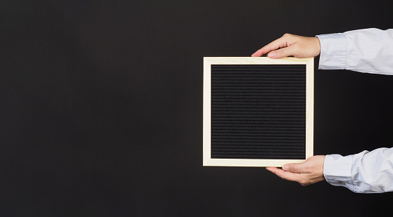 Black changeable letter board. In hands with horizontal frame.