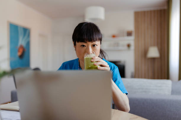 istock Asian Female Doctor Drinks a Smoothie While Working From Home 2073115522