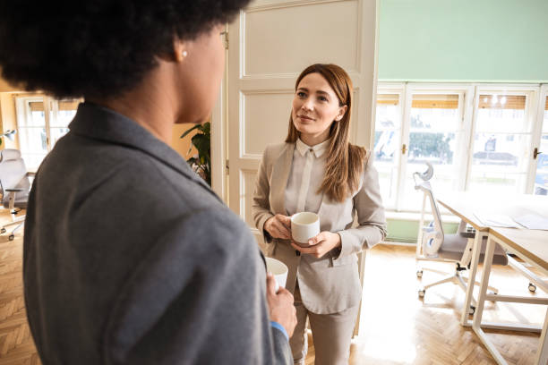 istock Businesswomen standing in the office having a discussion drinking coffee 2073152785