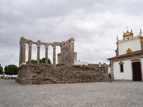 The Roman Temple of Évora, a UNESCO World Heritage Site, flanked by the Church of Lóios. In the historic center of the city of Évora. Portugal.