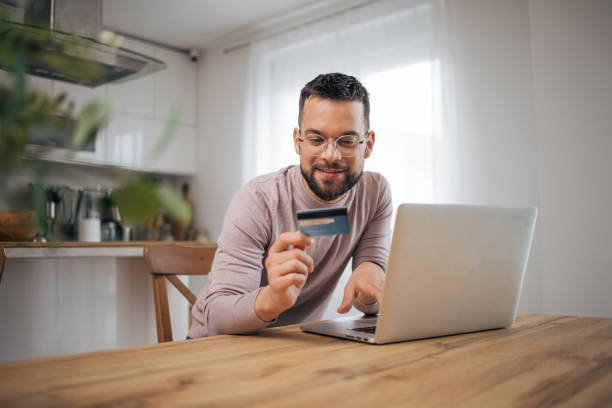 istock A man uses a laptop computer and a credit card. 2073223398