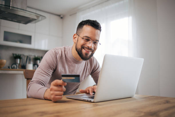 istock A man uses a laptop computer and a credit card. 2073225001