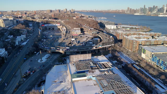 Lincoln Tunnel exit, crossing the waterfront area of snowy Weehawken, NJ. Manhattan skyline shown in the distance. Aerial footage with forward-descending camera motion