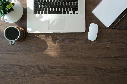 Laptop computer, coffee cup and notebook on wood background. Top view.