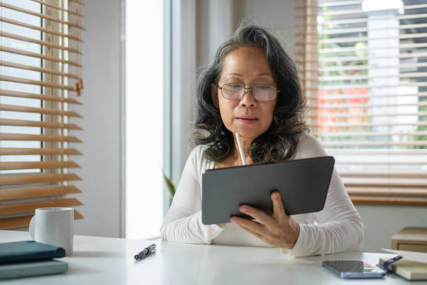istock Modern elderly senior woman in casual clothes using digital tablet at home. Retirement elderly technology concept. 2073247155