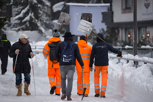 A resilient crew of high-visibility workers battles the aftermath of a heavy blizzard in Zermatt, skillfully utilizing snowplows and shovels to clear away the thick layers of snow, ensuring the Alpine village's safety and restoring the picturesque mountainous landscape.