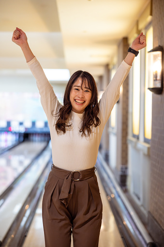 Woman raising hands for winning the game of bowling