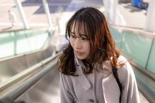 Business woman moving up on escalator in city