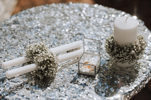Wedding accessories before the wedding ceremony. Candles decorated with gypsophila flowers, wedding rings for brides