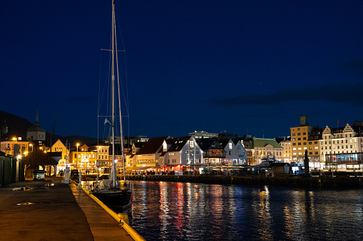 Bergen night time Cityscape with yacht in the foreground and reflections in the water