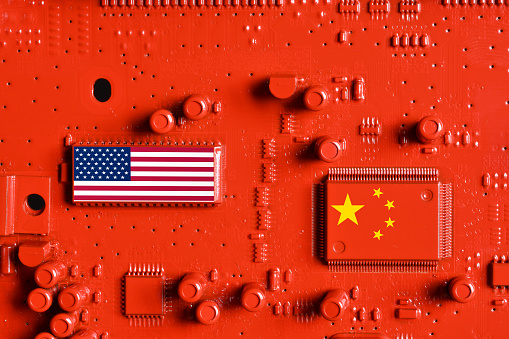 Flag of the Republic of China and USA on the microchips of a red painted printed electronic circuit board. Concept for supremacy in global microchip and semiconductor manufacturing.