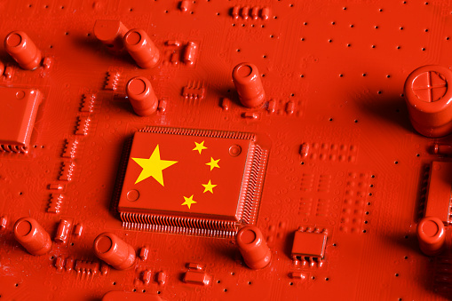 Flag of the Republic of China on microchip of a red painted printed electronic circuit board. Concept for supremacy in global microchip and semiconductor manufacturing.