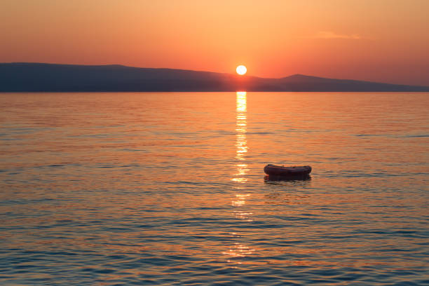 istock Lonely rubber boat in the rays of the setting sun 2073419225