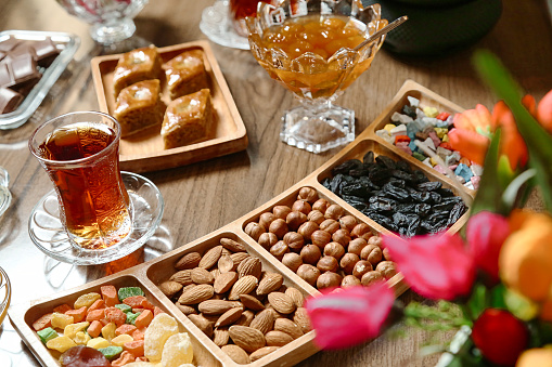 A wooden table covered with various trays of food and drinks displayed for a gathering or party.
