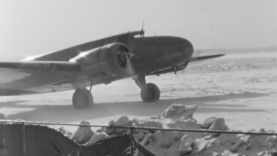 Evocative Image of 1930s Passenger Plane Stopped on Snowy Runway in New York with Engines On. Cloudy Sky and Snow on the Ground in a Sunny Winter Day. Boeing 247 of United Air Lines