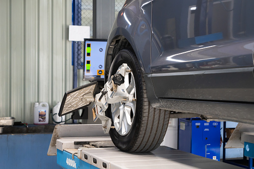 Car gets wheel alignment service at car service center, safe driving concept to reduce road accidents.