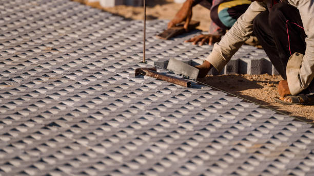 istock Installing paving blocks concept. Diligent man engages in outdoor construction work, laboriously installing paving blocks and cement to create a durable and well-crafted floor on construction site 2073451700