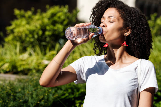 istock Thirsty curly woman drinking still-water in a park. 2073481212