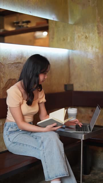 Asian woman working on her laptop at a cafe, embracing the flexibility of remote work. A stress-free environment enhances her focus