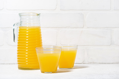 pitcher and two glasses of orange juice, closeup horizontal