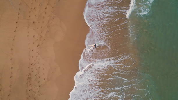istock Top view surfer walking on golden beach sand holding surfboard. Ocean rolling 2073547007