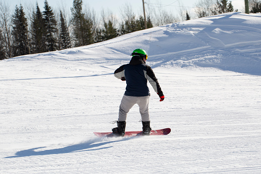 A smiling woman with a snowboard is walking with a snowboard in her hands at the ski slope.