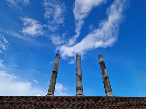Old columns against blue sky and clouds