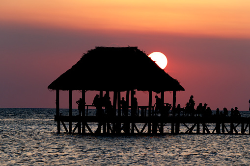 Sunset silhouette view of pier or hut in holbox at playa or punta cocos quintana roo mexico.
