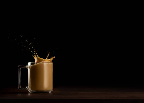 Mug of coffee with dynamic splash against dark backdrop stock photo