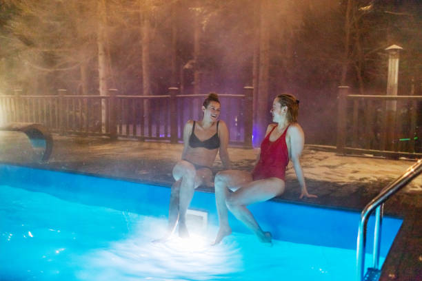 two females resting in pool in luxury hotel - apres ski lifestyles people blue ストックフォトと画像