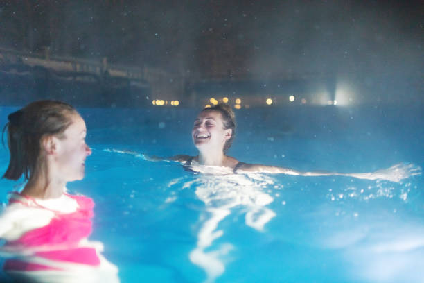two females resting in pool in luxury spa hotel - apres ski copy space happiness smiling ストックフォ��トと画像