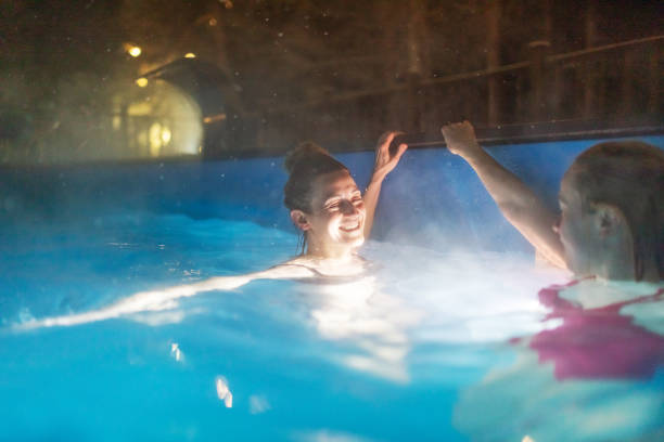 two females resting in pool in luxury spa hotel - apres ski copy space happiness smiling ストックフォトと画像