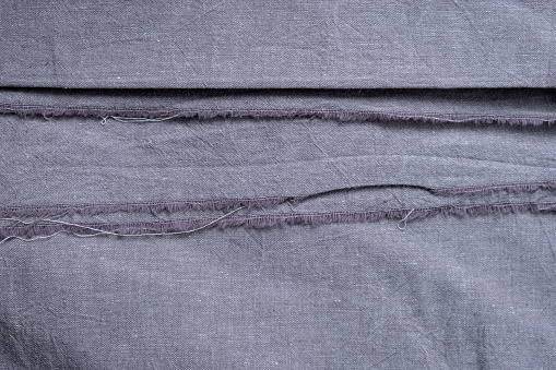 Natural linen fabric with a raw edges. Texture of linen fabric