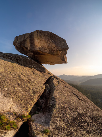 Giant balancing rock above the cliff. A natural geological phenomenon found at the Western Sayan. Natural Park Ergaki. Krasnoyarsk region. Russia. Vertical view.