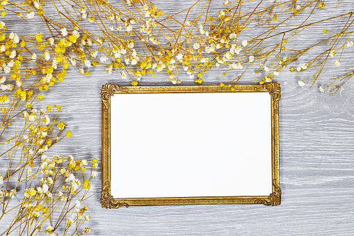 golden picture or photo frame mockup with pink baby's breath, gypsophila on gray wood table