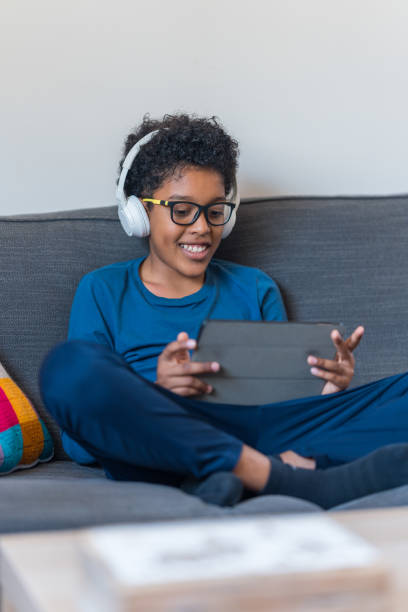 istock Young boy listening to music from digital tablet smiling 2073681027