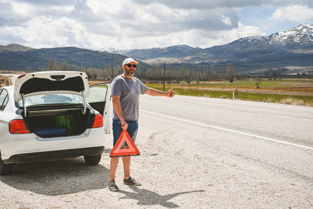 man stands by a broken car - stranded travel people traveling disappointment - fotografias e filmes do acervo