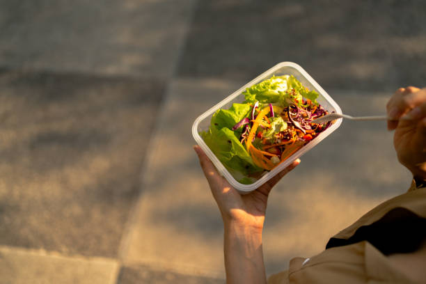 istock Enjoying a Fresh Mixed Salad from a Plastic Container - A Healthy Meal Anywhere Concept 2073694071
