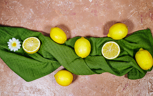fresh yellow lemons above green napkin with daisy flower on wood table, Gardening concept, lemonade