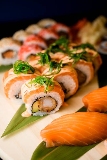 istock Assorted sushi rolls with crab sticks and salmon on a wooden board on black table 2073724767