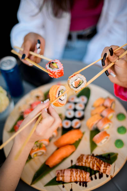 istock Three pretty young women are chomping at the bit with sushi rolls on a blurred background 2073752587