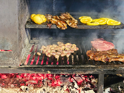 On the bottom grill: chicken hearts and chorizo. On the top, potatoes, beef ribs and orange slices.