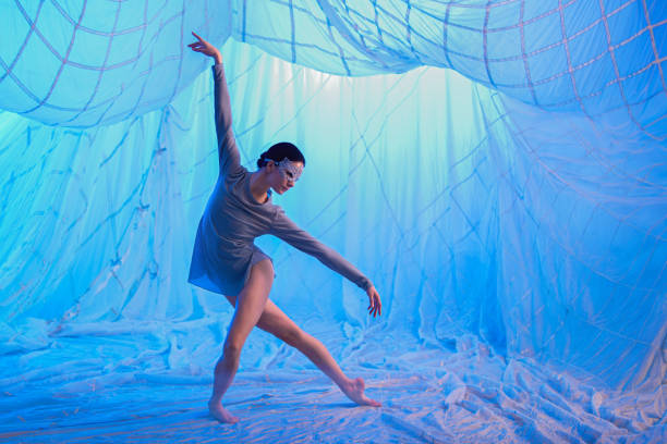 a woman dances in a room with white drapes made of thin airy fabric, illuminated by blue spotlights. - chiton zdjęcia i obrazy z banku zdjęć