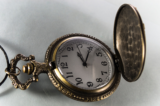Antique clock, beautiful details of an old pocket watch on rustic wooden surface, selective focus.