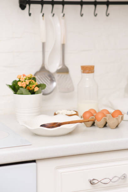 istock Ingridients for prepairing dough on a white kitchen table : eggs, bottle of milk, cottage, plate with wooden spoon. 2073853508