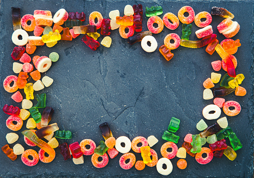 Colorful candies, jelly and marmalade on stone background. Top view with copy space